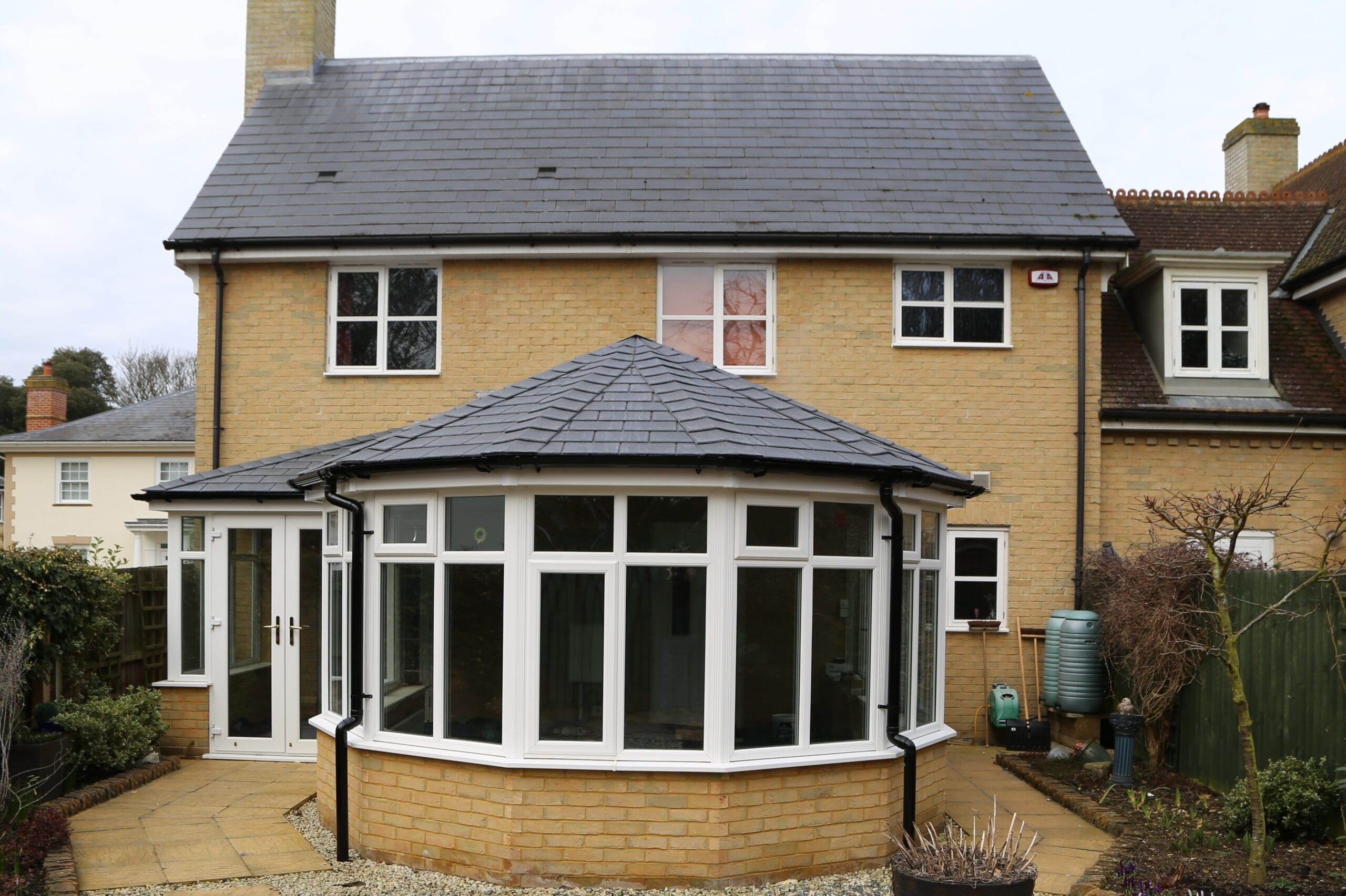 7 P shape conservatory with a dark tiled roof and bay window on a yellow brick base