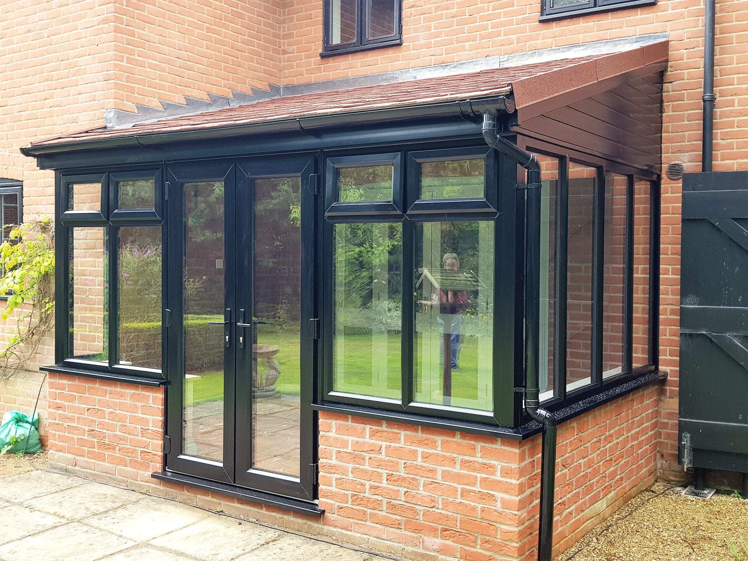 External of Black Conservatory | Insulated Conservatory Company | Insulated Conservatory Company Anthracite grey lean-to conservatory with a brick base and French doors