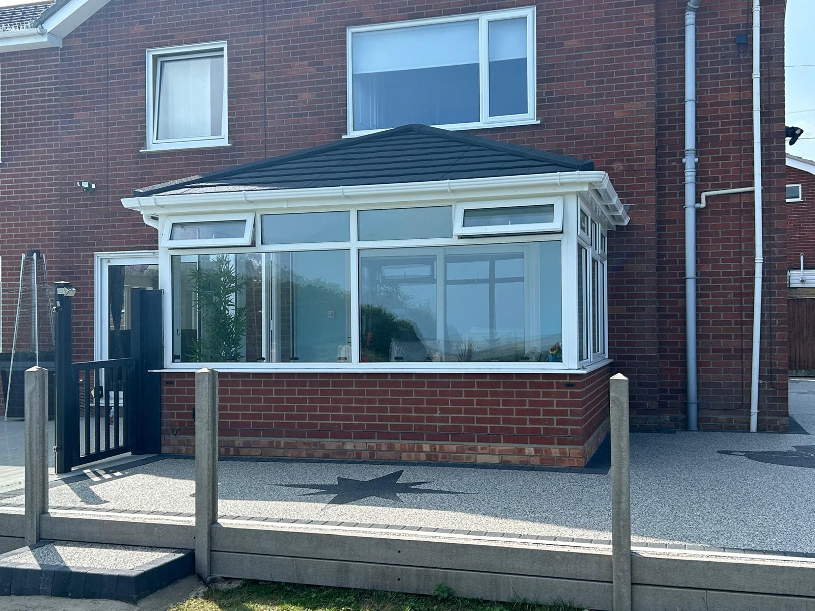Edwardian conservatory with a dark solid roof above a raised deck